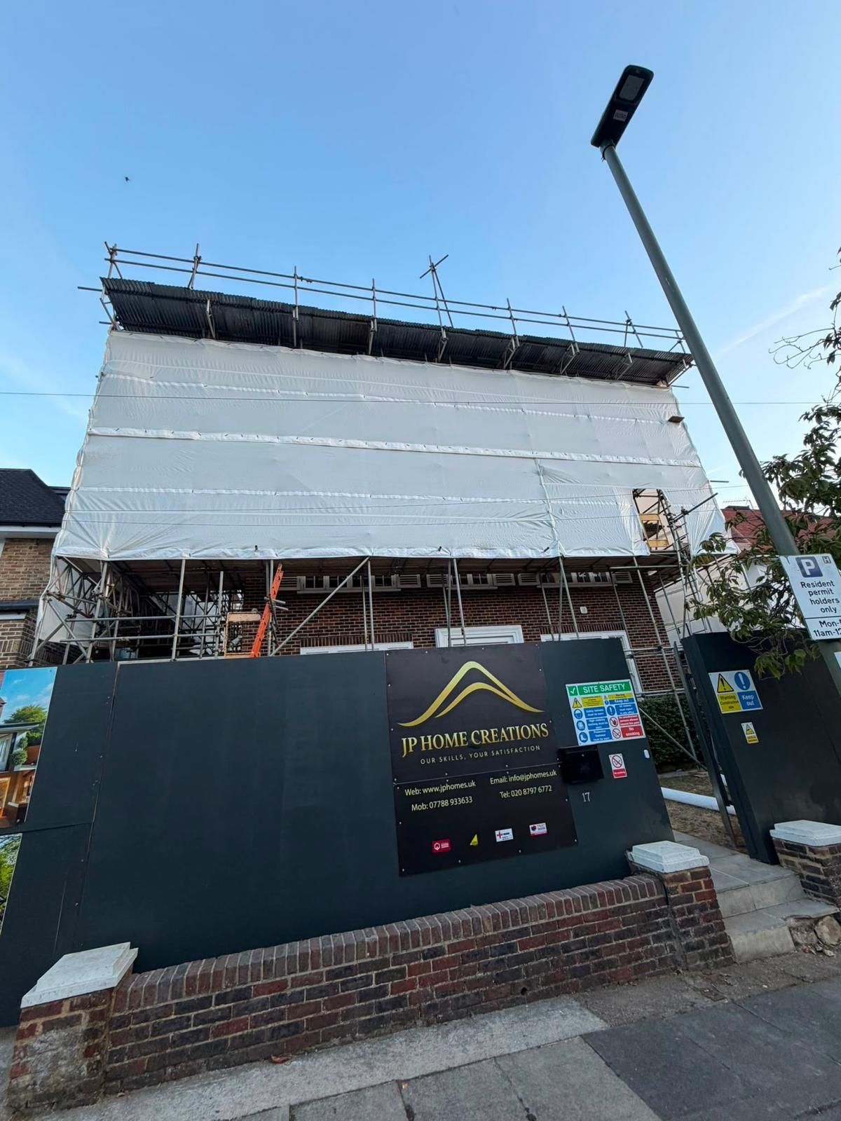 Front view of a fully sheeted temporary roof scaffold above a residential building site
