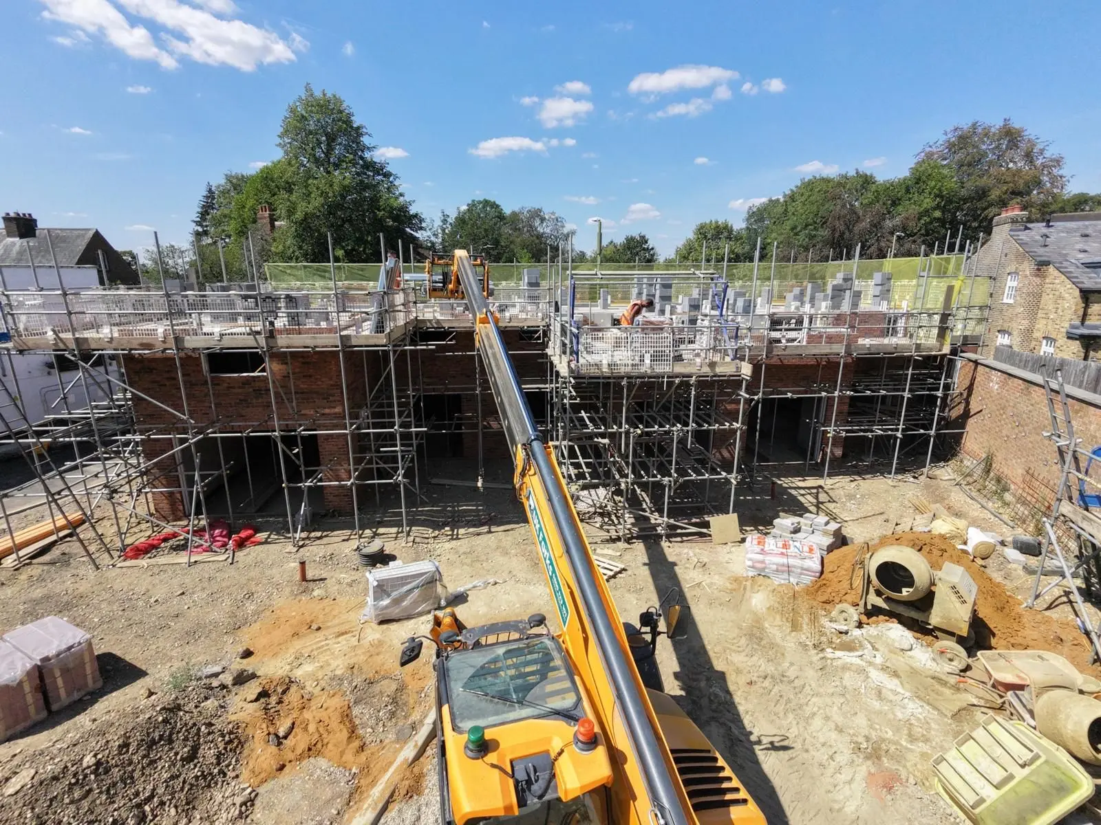 Scaffolding and edge protection around a new build development at first floor slab stage with a telehandler on site