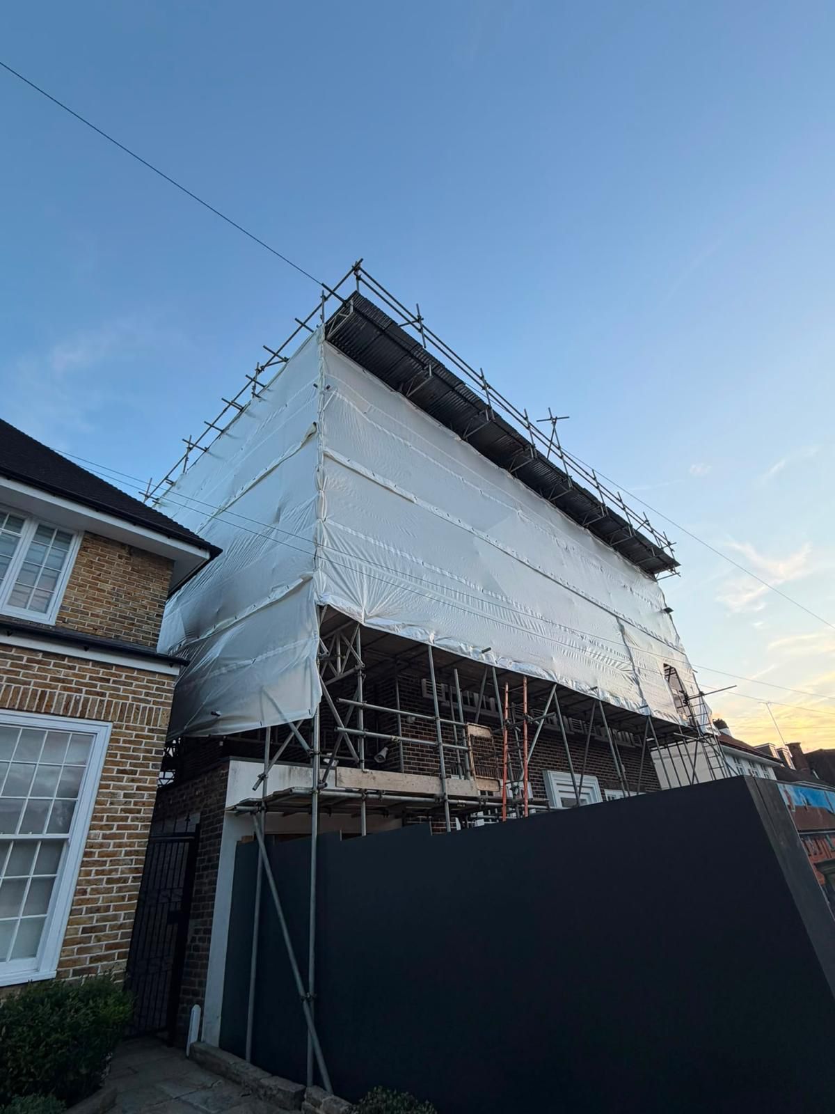 Corner view of a weatherproof temporary roof scaffold enclosing a residential development