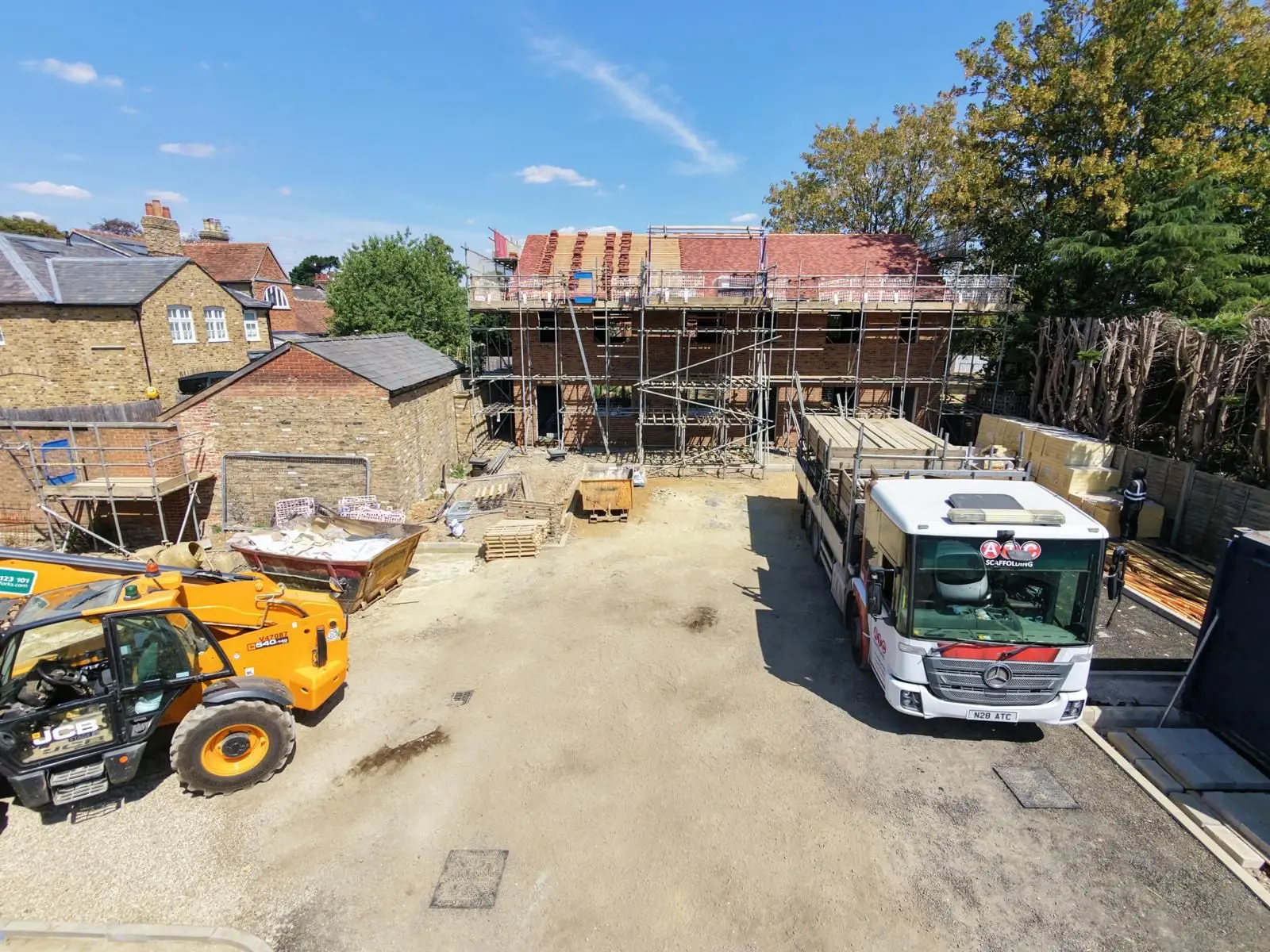 ATC Scaffolding lorry on a new build site with scaffolding erected around a partially roofed two-storey development