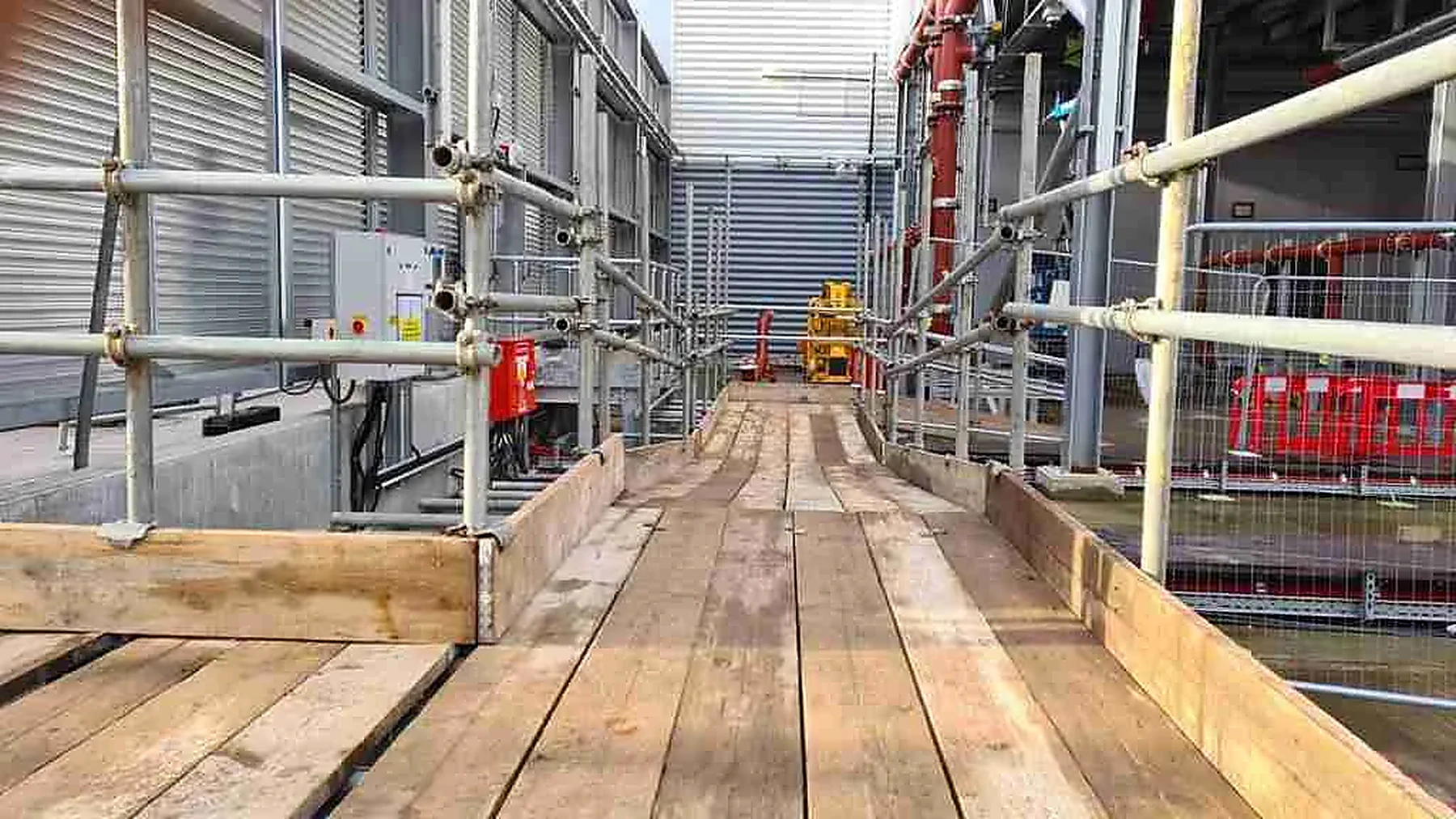 Scaffolding erected around a technical facility building under construction with a tower crane overhead