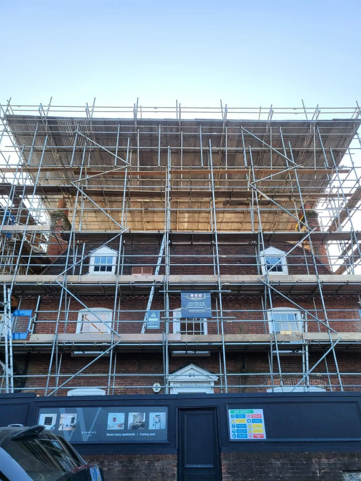 Front elevation of a residential building protected by a temporary roof scaffold during redevelopment